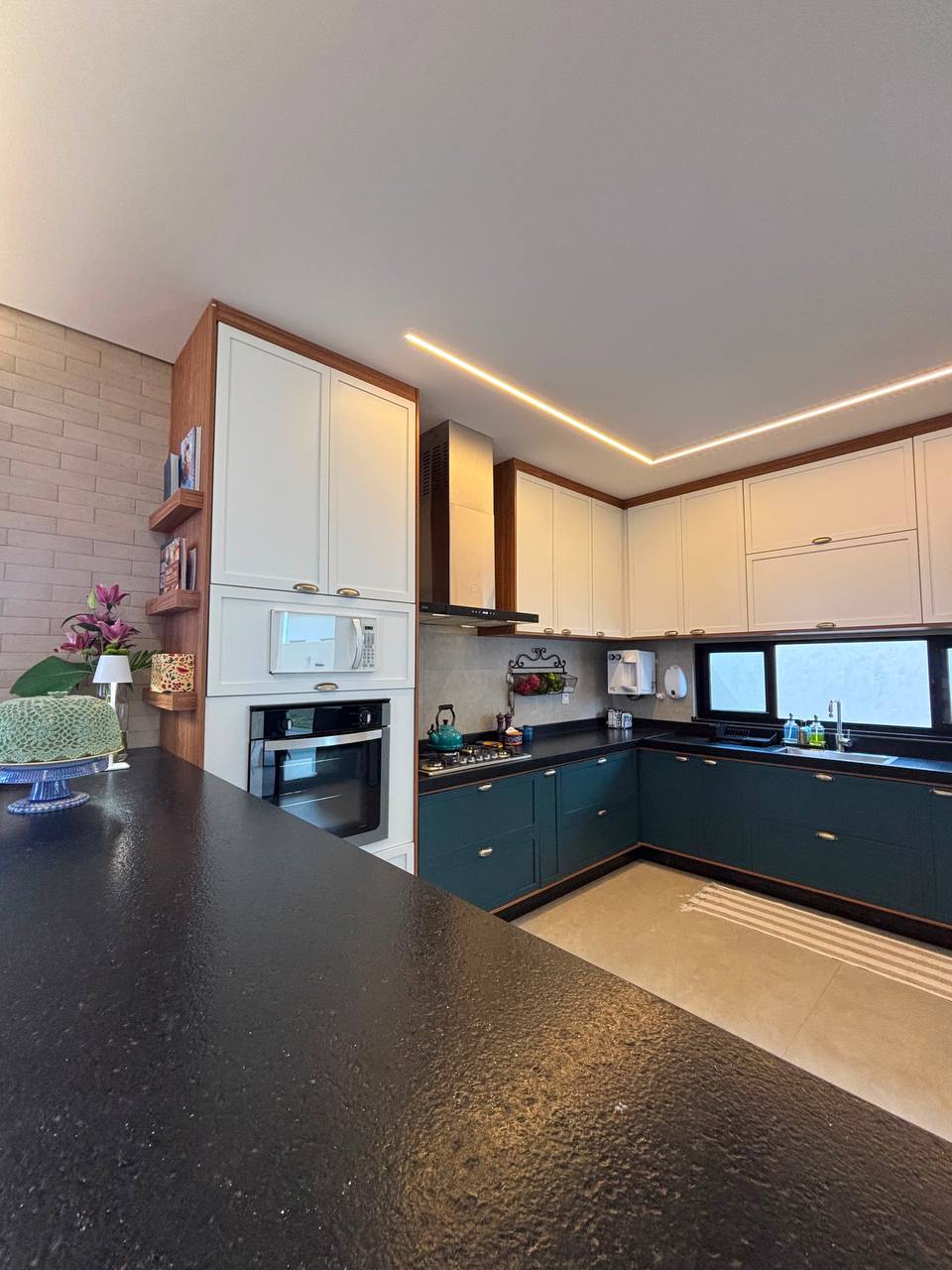 Cozinha planejada com marcenaria verde, armários claros e iluminação linear